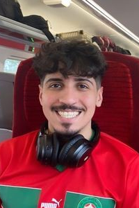 Elyas smiling sat on a train.