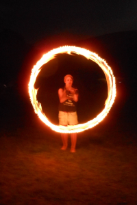 Jo spinning fire in field.